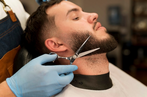 Jonge man die zijn baard laat stylen bij de kapper