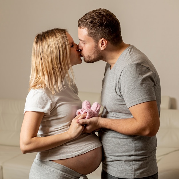 Gratis foto jonge man die zijn zwangere vrouw kust