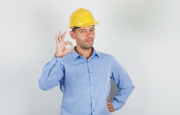 Jonge man doet ok teken in shirt, helm en op zoek gelukkig