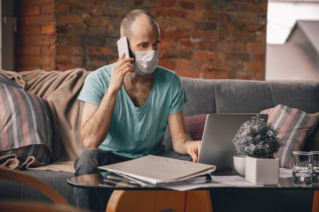 Jonge man doet yoga thuis terwijl hij in quarantaine en freelance werkt