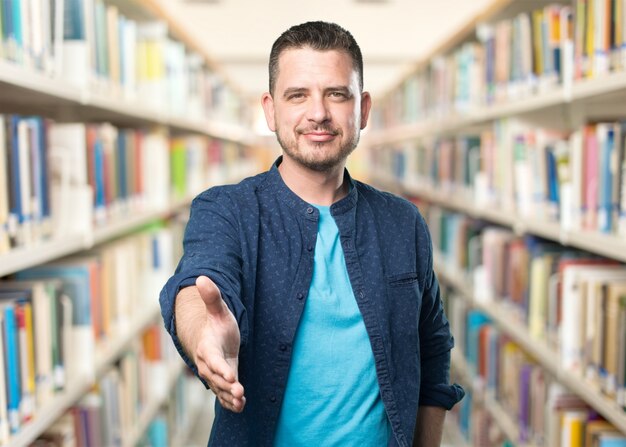 Jonge man draagt ​​een blauwe outfit. Het aanbieden van zijn hand.