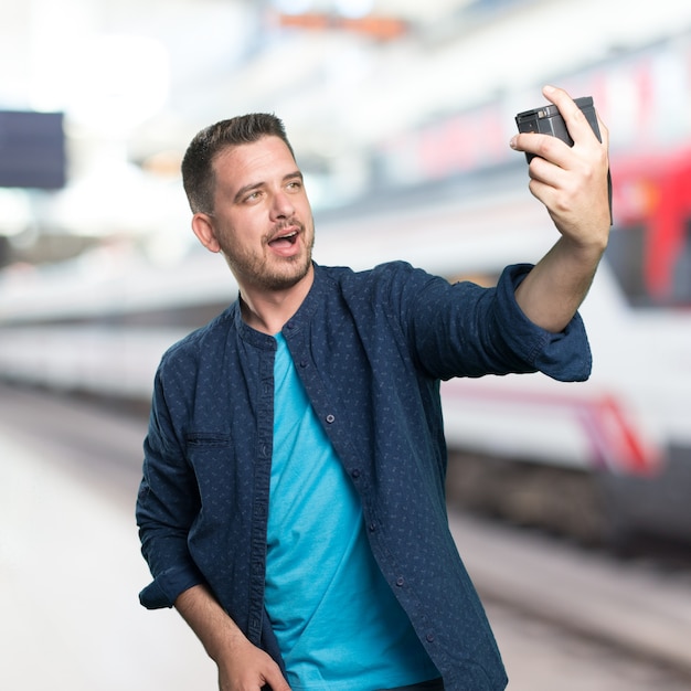 Jonge man draagt ​​een blauwe outfit. Het nemen van een selfie.