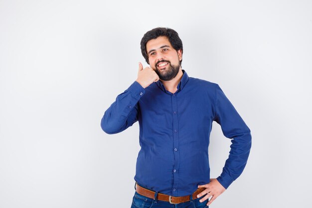 Jonge man duim opdagen in koningsblauw shirt, vooraanzicht.