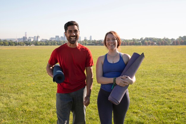 Jonge man en vrouw buiten met yogamatten