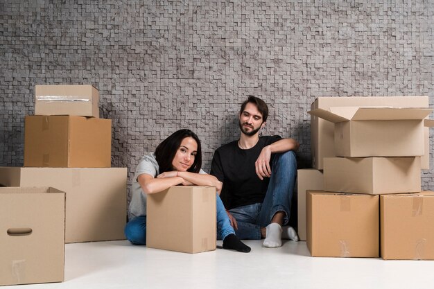 Jonge man en vrouw die dozen voor verhuizing voorbereiden