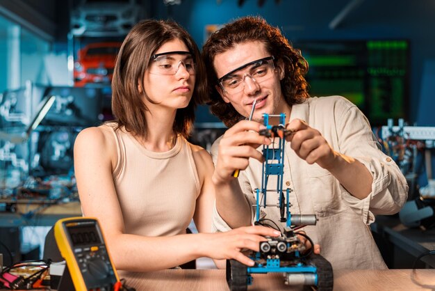 Jonge man en vrouw in beschermende bril doen experimenten in robotica in een laboratorium Robot