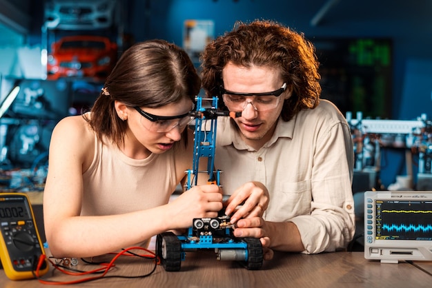 Jonge man en vrouw in beschermende bril doen experimenten in robotica in een laboratorium Robot