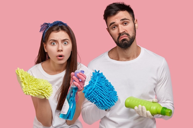 Jonge man en vrouw poseren met schoonmaakmiddelen