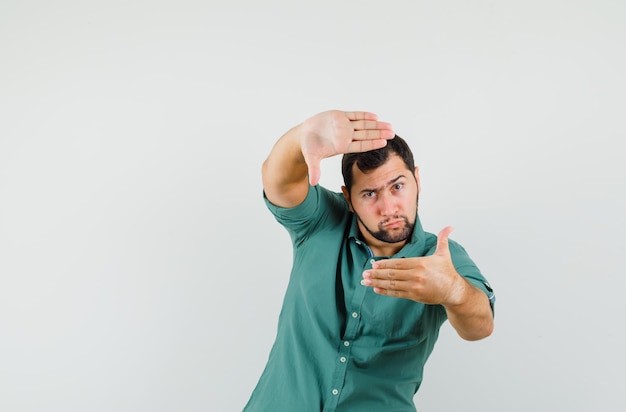 Jonge man frame gebaar maken in groen shirt vooraanzicht.