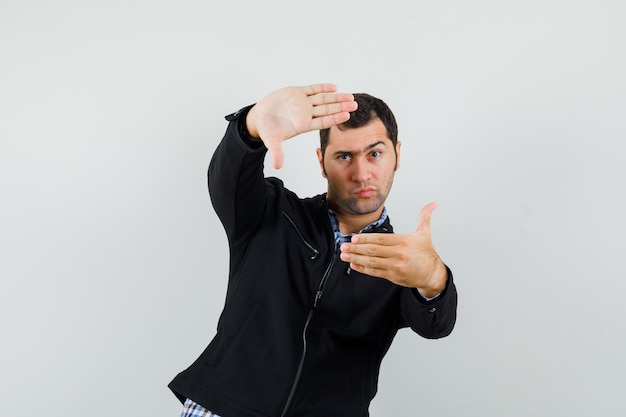 Jonge man frame gebaar maken in shirt, jasje en voorzichtig kijken