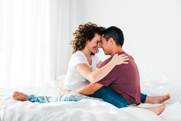 Jonge man gelukkige vrouw omarmen op bed