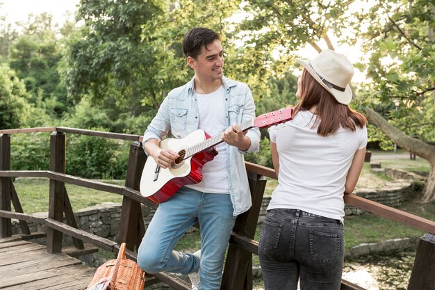 Jonge man gitaarspelen aan zijn vriendin