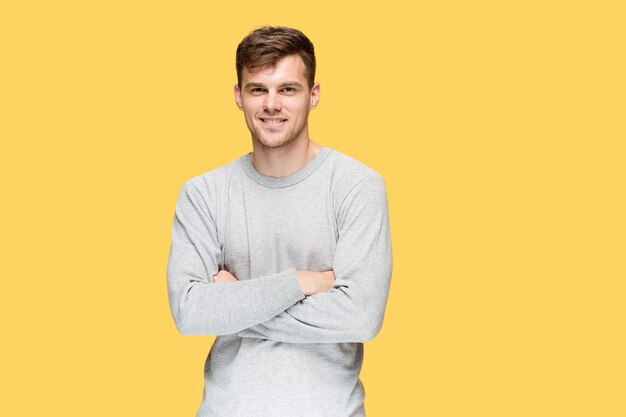 jonge man glimlachend en camera kijken op gele studio achtergrond
