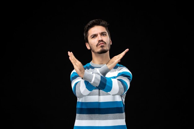 Jonge man in blauw gestreepte trui die handen kruist in een verbiedend gebaar