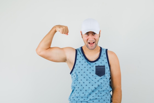 Jonge man in blauw hemd, pet die de spieren van de arm toont en er zelfverzekerd uitziet