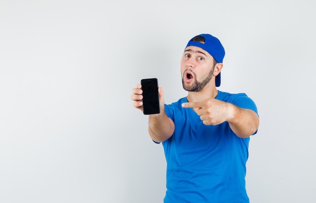 Jonge man in blauw t-shirt en pet wijzend op mobiele telefoon