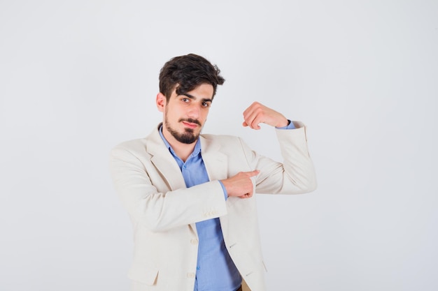 Jonge man in blauw t-shirt en wit colbert die spieren toont en er serieus uitziet?