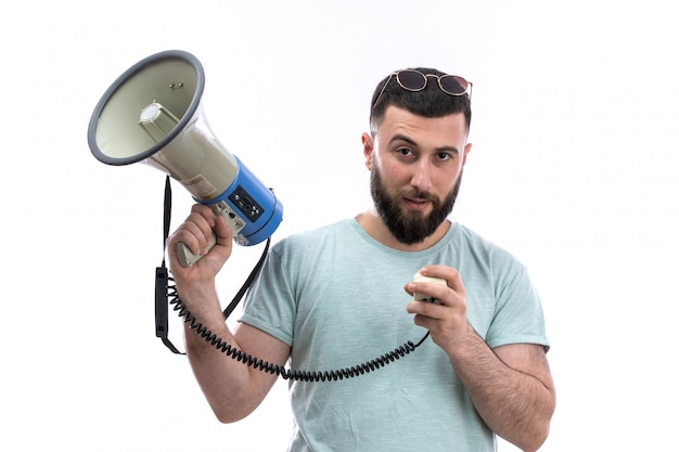 Jonge man in blauw t-shirt met baard en zonnebril met megafoon