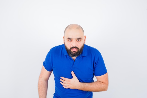 Jonge man in blauw t-shirt met buikpijn