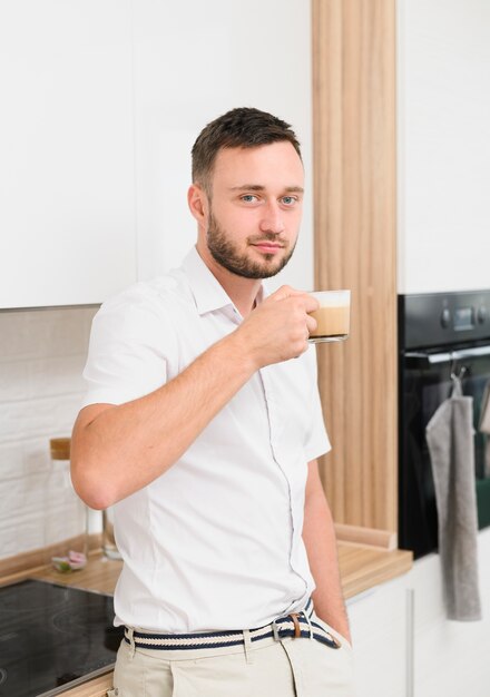 Jonge man in de keuken met een cappuccino