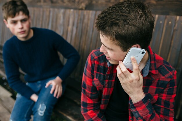Jonge man in een geruite overhemd praten over smartphone