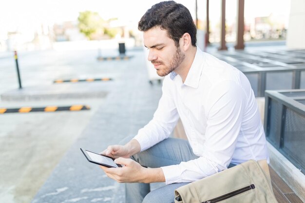 Jonge man in formele kleding leest zijn favoriete roman met een e-reader