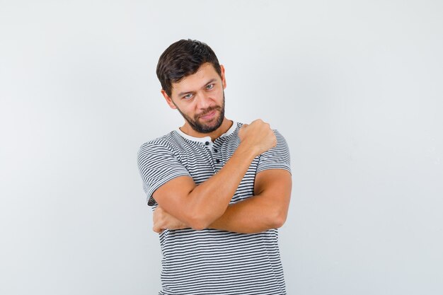 Jonge man in gestreept t-shirt met gebalde vuist en zelfverzekerd, vooraanzicht.