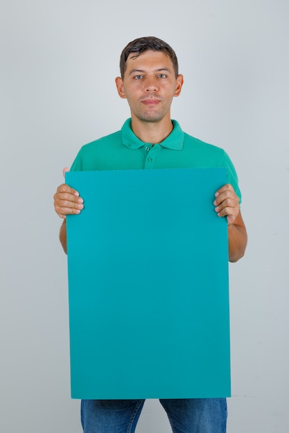 Jonge man in groen t-shirt met blauwe poster, vooraanzicht.