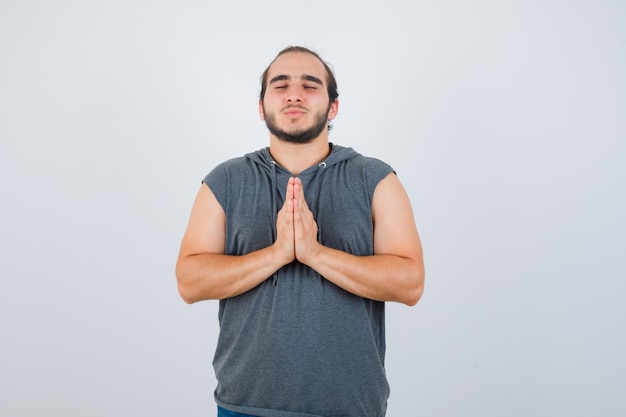 Jonge man in hoodie namaste gebaar tonen en op zoek ontspannen, vooraanzicht.