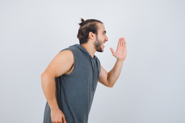 Jonge man in mouwloze hoodie rennen en kijken vrolijk, vooraanzicht.