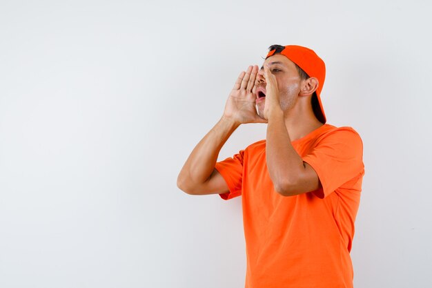 Jonge man in oranje t-shirt en pet schreeuwen