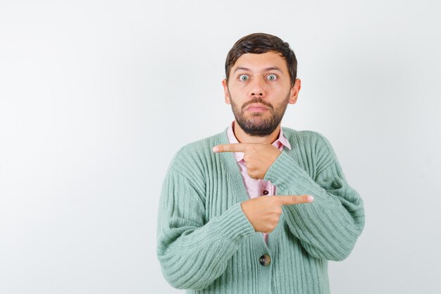 Jonge man in overhemd, vest wijzend naar beide kanten en aarzelend kijkend, vooraanzicht.