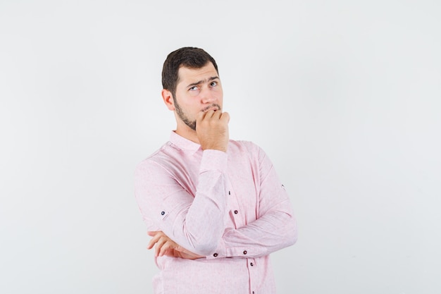 Jonge man in roze shirt opzoeken en nadenkend kijken