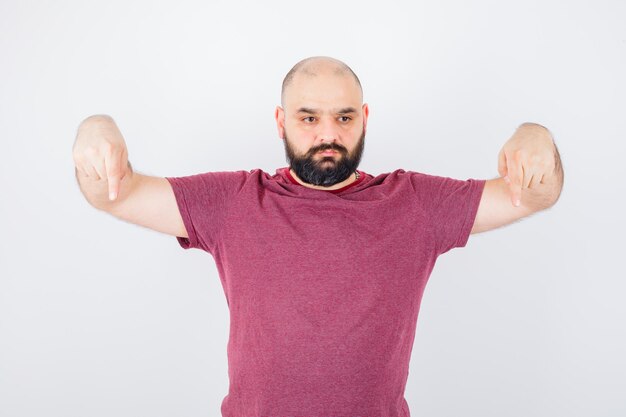 Gratis foto jonge man in roze t-shirt naar beneden, vooraanzicht.