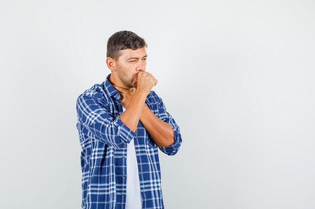 Jonge man in shirt hoest lijden en ziek, vooraanzicht kijken.