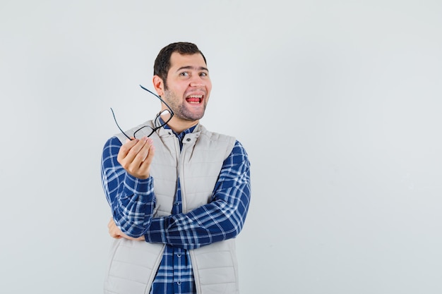 Jonge man in shirt, jasje met bril terwijl praten en vrolijk kijken, vooraanzicht. ruimte voor tekst