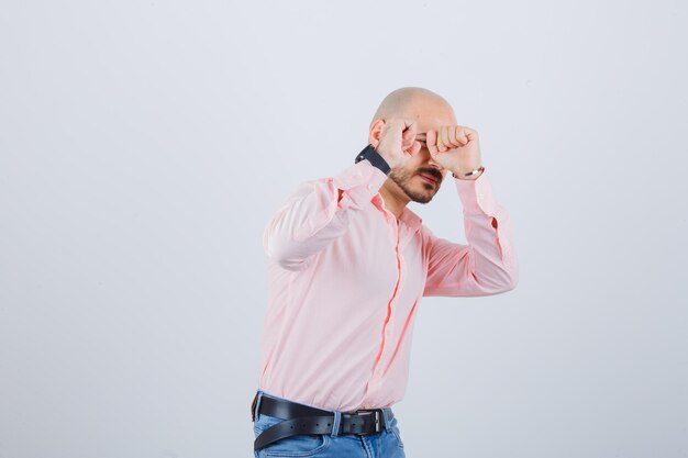 Jonge man in shirt, spijkerbroek die doet alsof hij zichzelf verdedigt en er bang uitziet, vooraanzicht.