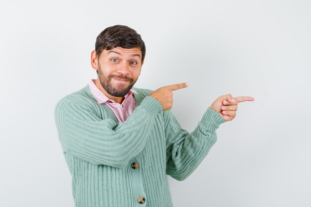 Jonge man in shirt, vest naar rechts wijzend en vrolijk, vooraanzicht.