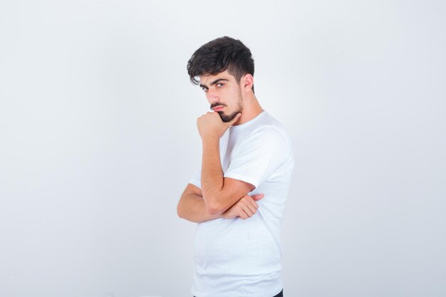 Jonge man in t-shirt poseren terwijl hij staat en er zelfverzekerd uitziet