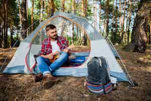 Gratis foto jonge man in tent spelen quitar