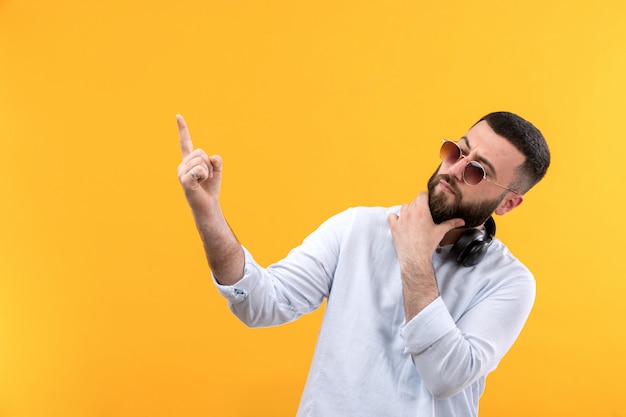 Jonge man in wit overhemd met baard, zonnebril en zwarte hoofdtelefoon