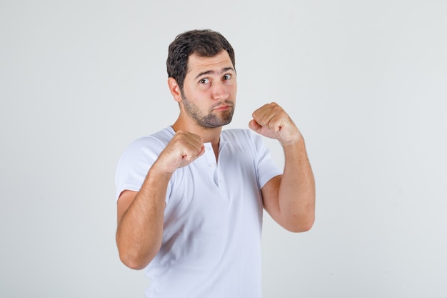 Jonge man in wit t-shirt die zich voordeed als een bokser en er sterk uitziet