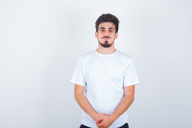 Jonge man in wit t-shirt kijkt naar voren en ziet er zelfverzekerd uit