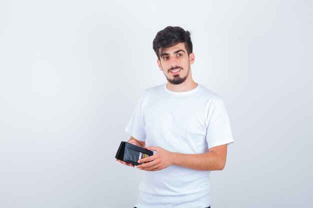 Jonge man in wit t-shirt met portemonnee en peinzend kijkend