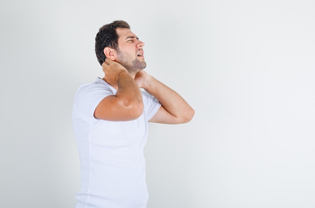 Jonge man in wit t-shirt nekpijn lijden en op zoek pijnlijk