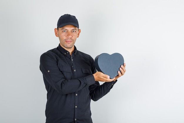 Jonge man in zwart shirt met de doos van de gift van de glbholding