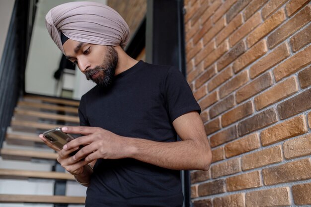 Jonge man in zwarte t-shirt sms't aan de telefoon en kijkt betrokken