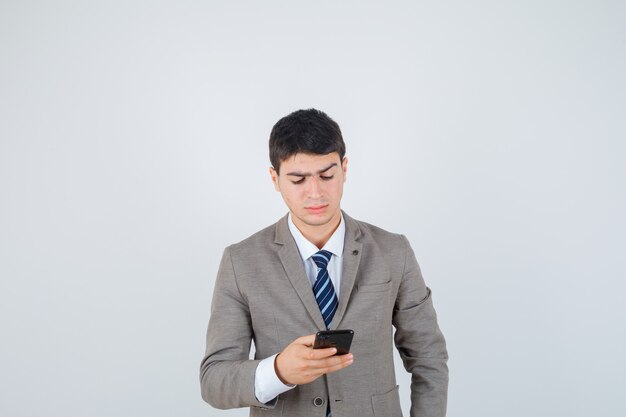 Jonge man kijkt naar telefoon in formeel pak