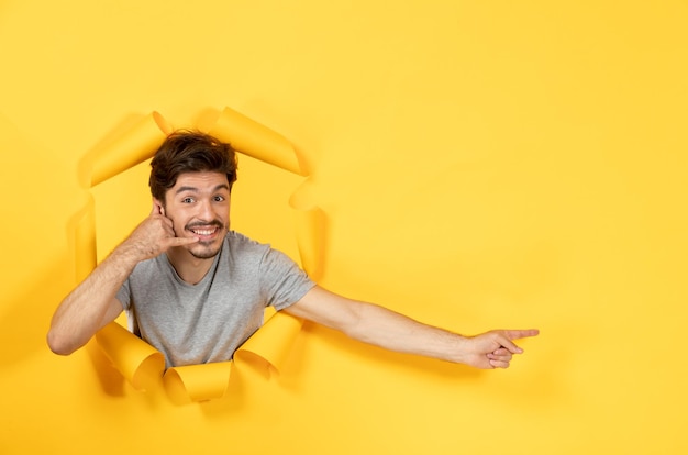 Jonge man kijkt uit gescheurd geel papier oppervlak indoor man gezichtsuitverkoop