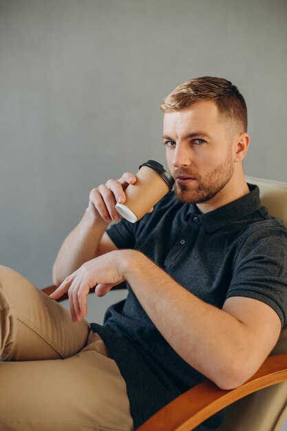 Jonge man koffie drinken in een comfortabele stoel